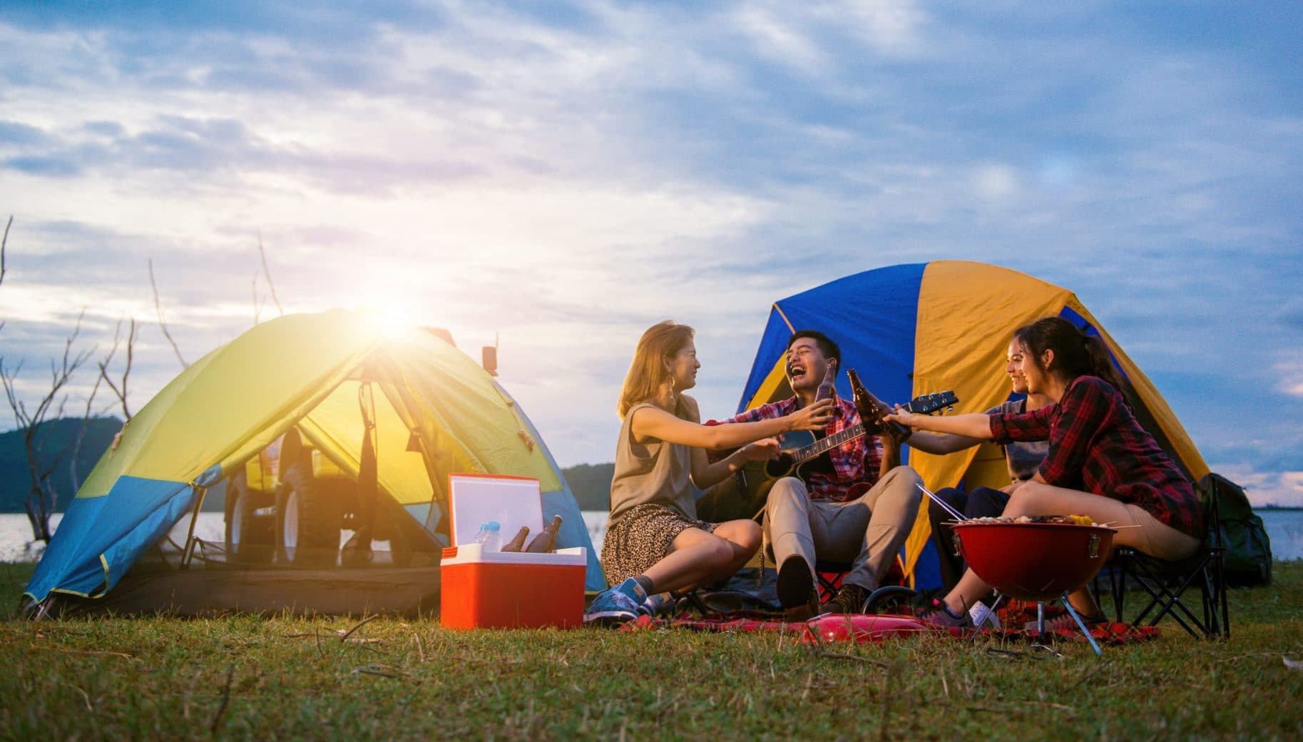 Friends camping, having a BBQ and singing songs with a guitar