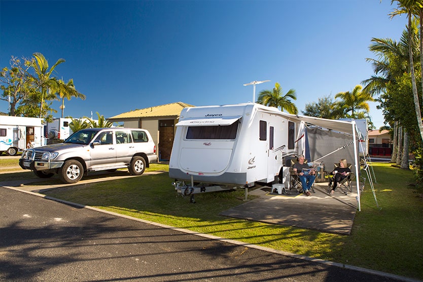 Family relaxing around their caravan camp on an ensuite site at Brisbane Holiday Village