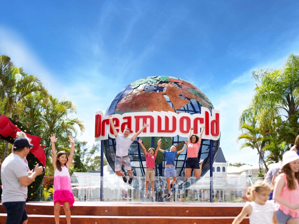 Family jumping for joy in front of Dreamworld theme park sign